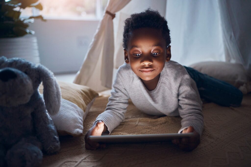 I have so many stories. Shot of a little boy using his digital tablet while lying on the floor.